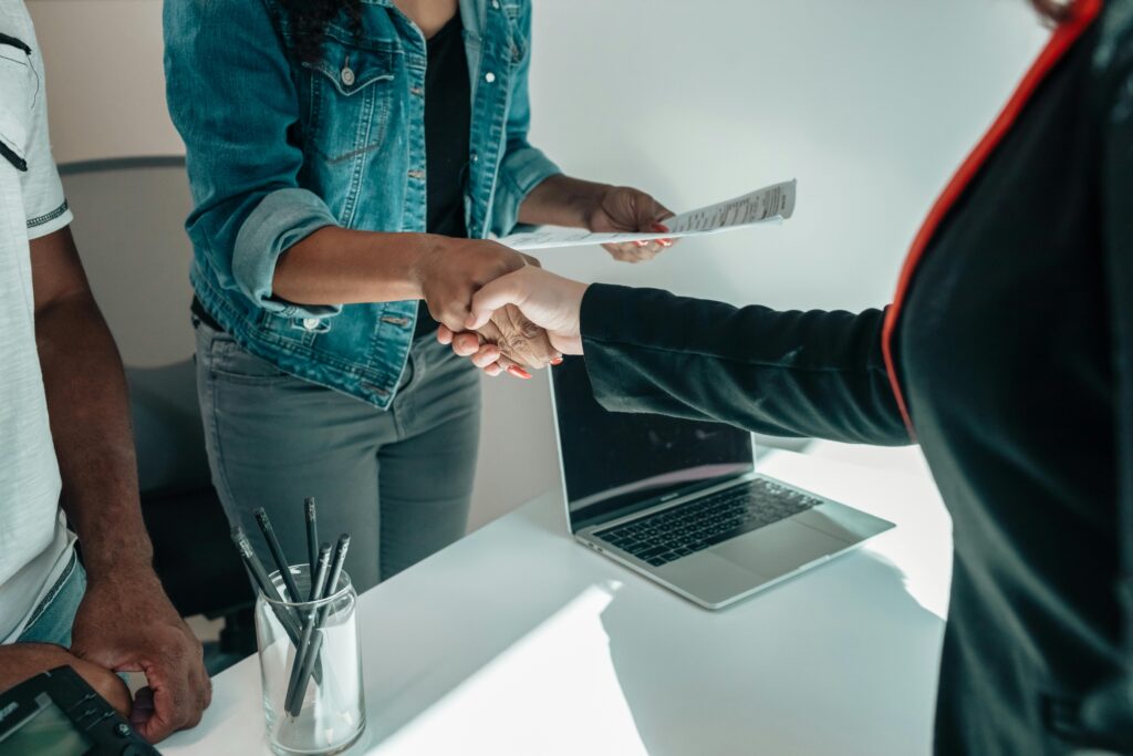 Two people shaking hands over a desk signifies a business agreement or partnership.